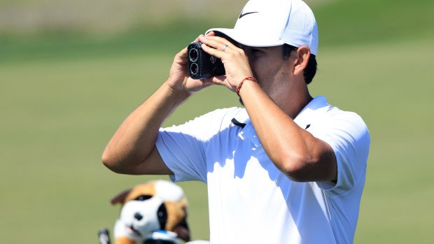 Tour caddie Harry Diamond using a rangefinder during a practice round.