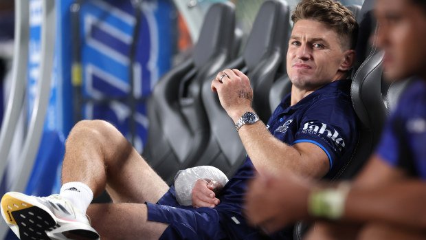 Beauden Barrett of the Blues sits on the bench with an icepack on his wrist.