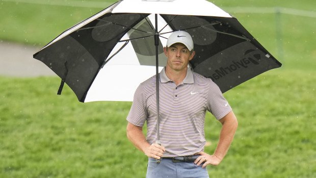 Rory McIlroy of Northern Ireland holds an umbrella on the 11th green.