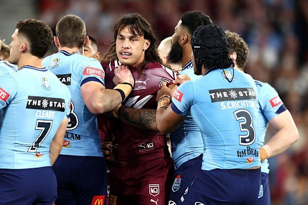 Tino Fa'asuamaleaui of the Maroons is pulled away by NSW Blues players.