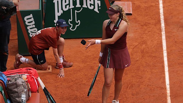 Mirra Andreeva tosses the wristband received from Daria Kasatkina onto her tennis bag.