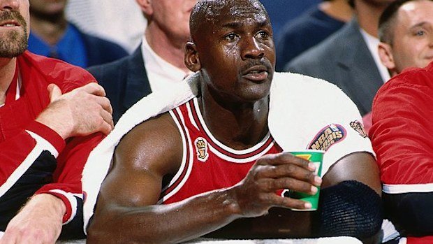 Michael Jordan sits on the bench wrapped in towels.