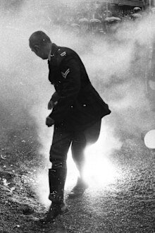 A policeman loses his hat as he runs from a smoke bomb during rioting by 1971 anti-apartheid demonstrators.