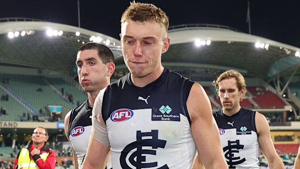 Patrick Cripps of the Blues and Jacob Weitering lead their teammates off.
