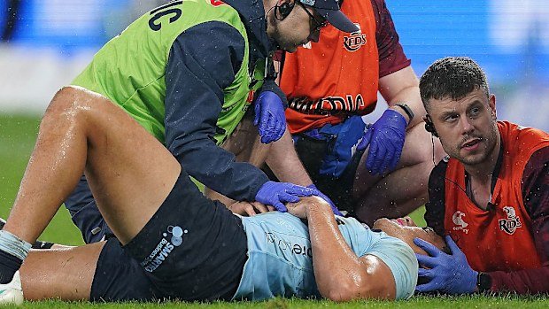 Joseph-Aukuso Suaalii of the Waratahs receives treatment for an injury before being stretchered off.